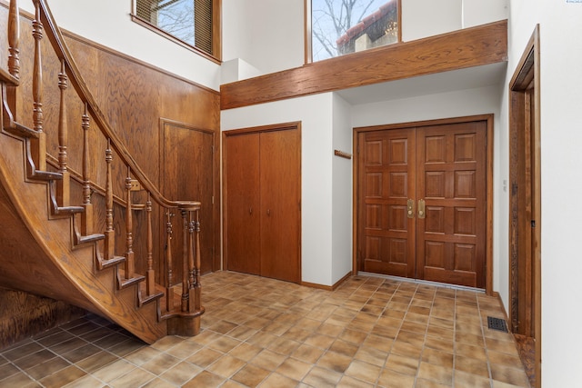 entrance foyer with stairs, a high ceiling, plenty of natural light, and visible vents