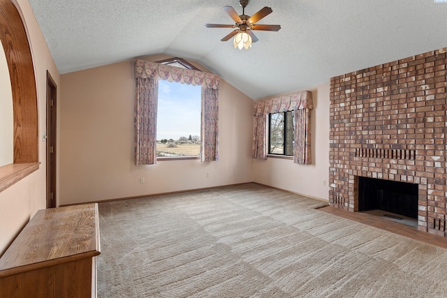 unfurnished living room with a brick fireplace, carpet, lofted ceiling, a textured ceiling, and a ceiling fan