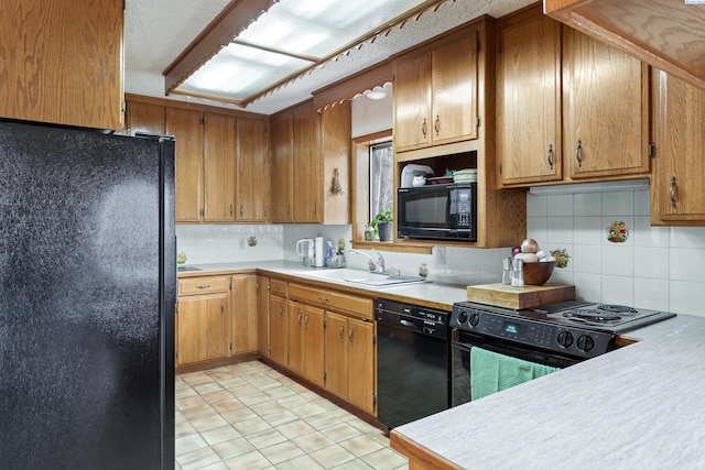 kitchen featuring brown cabinets, black appliances, a sink, tasteful backsplash, and light countertops