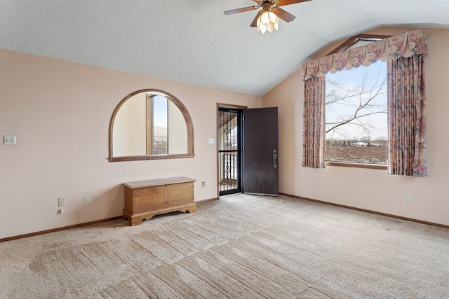 carpeted foyer featuring baseboards, a textured ceiling, a ceiling fan, and vaulted ceiling