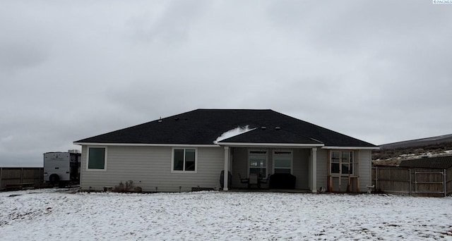 snow covered house featuring fence