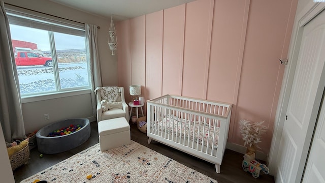 bedroom with a crib and dark wood finished floors