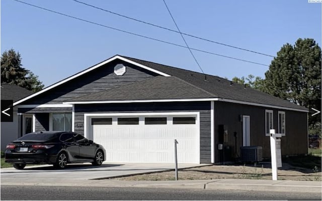 view of front facade featuring cooling unit, roof with shingles, driveway, and an attached garage