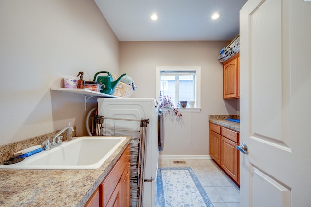 laundry area featuring cabinets, light tile patterned flooring, and sink