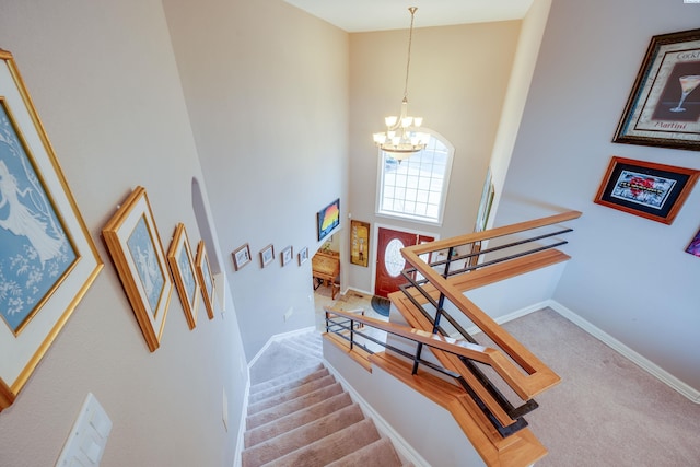 staircase with carpet flooring, a notable chandelier, and a high ceiling