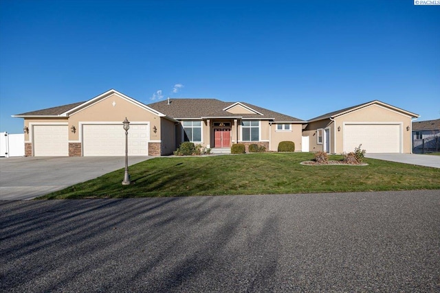 single story home featuring an attached garage, a front yard, concrete driveway, and stucco siding