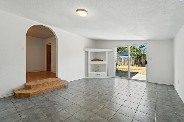 323 S Beech St, Kennewick, WA 99336 - empty room with arched walkways, a textured ceiling, and tile patterned flooring
