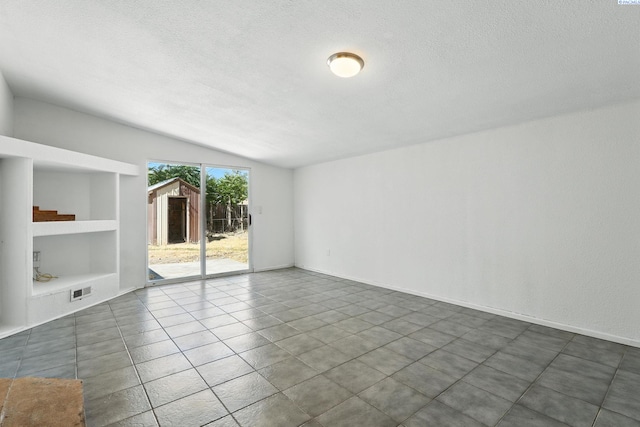 323 S Beech St, Kennewick, WA 99336 - empty room with lofted ceiling, a textured ceiling, built in features, and dark tile patterned flooring