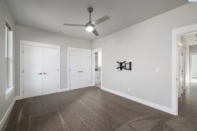 unfurnished bedroom with carpet flooring, two closets, and ceiling fan