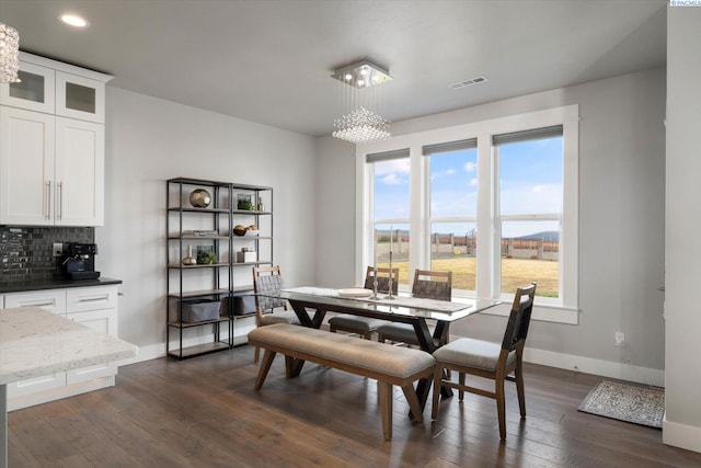 dining area with dark hardwood / wood-style floors and an inviting chandelier