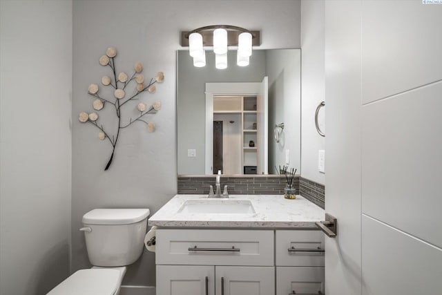 bathroom featuring vanity, backsplash, and toilet