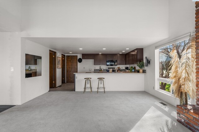 unfurnished living room with light carpet, a towering ceiling, and recessed lighting