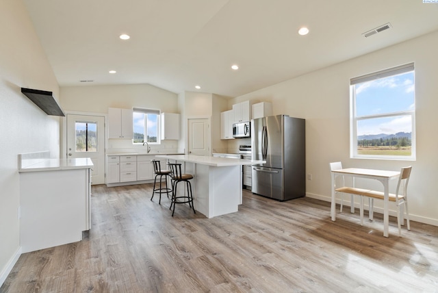 kitchen featuring white cabinets, appliances with stainless steel finishes, light wood-style floors, a center island, and visible vents