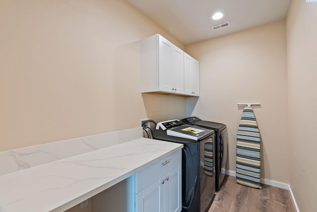 washroom featuring visible vents, washing machine and dryer, cabinet space, baseboards, and light wood-style floors