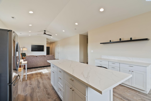 kitchen featuring light wood finished floors, a center island, freestanding refrigerator, white cabinetry, and vaulted ceiling