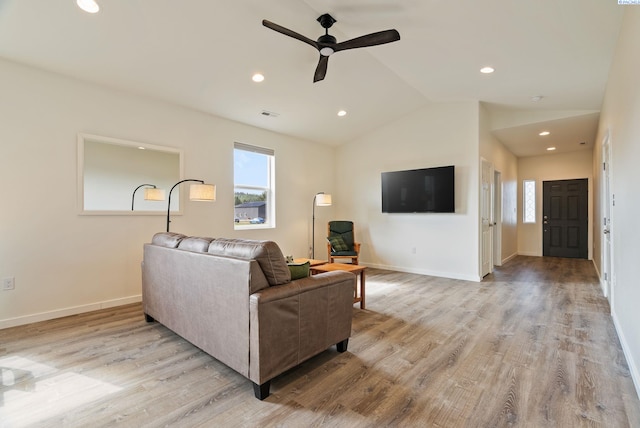 living area with a healthy amount of sunlight, ceiling fan, light wood-type flooring, and lofted ceiling