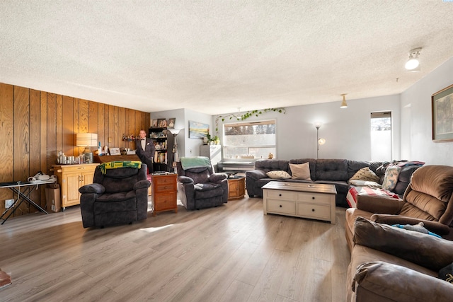 living room featuring wood walls, a textured ceiling, light hardwood / wood-style flooring, and a wealth of natural light