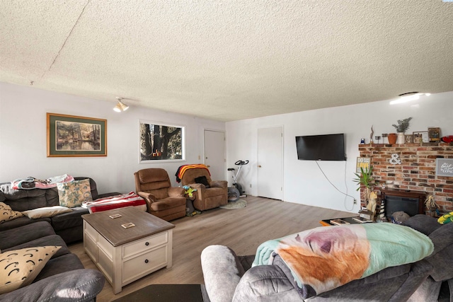 living room featuring a brick fireplace, hardwood / wood-style floors, and a textured ceiling