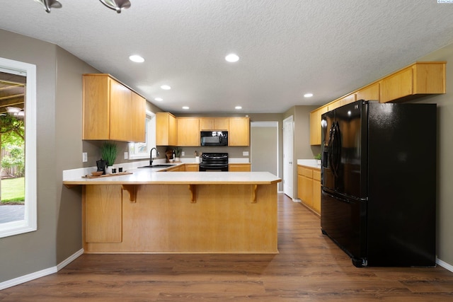 5501 Maui Ct, West Richland, WA 99353 - kitchen featuring black appliances, a peninsula, a sink, light countertops, and dark wood finished floors