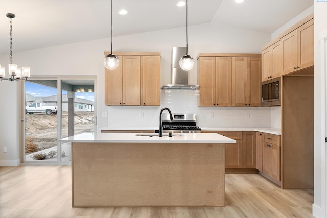 kitchen with pendant lighting, an island with sink, stainless steel range oven, and wall chimney exhaust hood