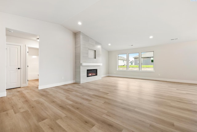 unfurnished living room with a fireplace, light hardwood / wood-style floors, and vaulted ceiling