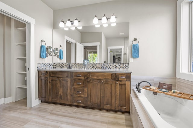 bathroom featuring double vanity, decorative backsplash, a sink, and a garden tub