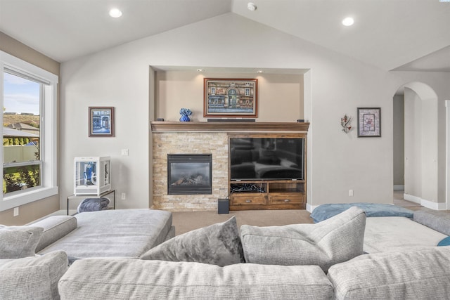 living room featuring arched walkways, vaulted ceiling, a glass covered fireplace, carpet flooring, and recessed lighting