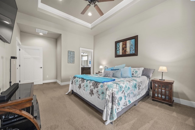 carpeted bedroom with connected bathroom, a raised ceiling, baseboards, visible vents, and ornamental molding