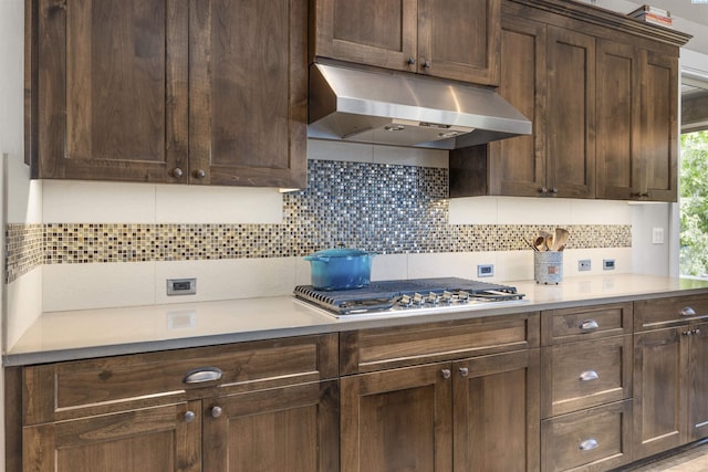 kitchen with light countertops, backsplash, under cabinet range hood, and dark brown cabinetry