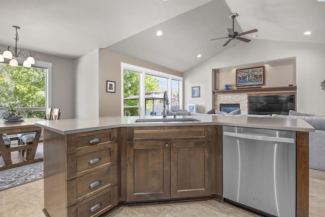 kitchen featuring stainless steel dishwasher, a fireplace, open floor plan, light countertops, and a sink