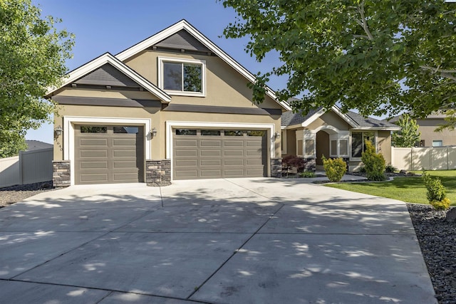 craftsman-style house featuring a garage, fence, stone siding, stucco siding, and driveway