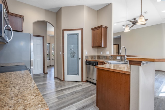 615 N Larkspur Dr, Othello, WA 99344 - kitchen featuring arched walkways, a sink, appliances with stainless steel finishes, a peninsula, and light wood-style flooring