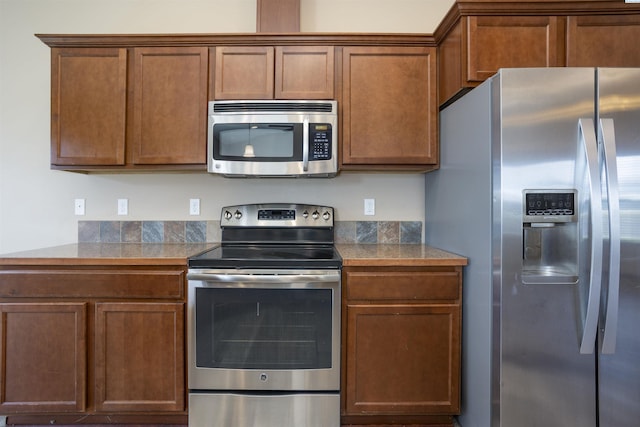 615 N Larkspur Dr, Othello, WA 99344 - kitchen featuring brown cabinetry, tile countertops, and stainless steel appliances