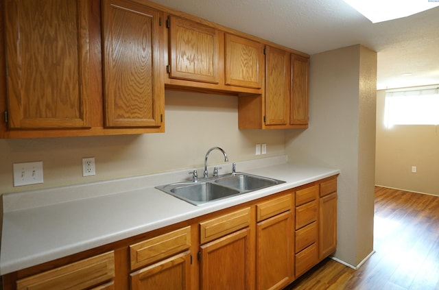 1004 NE D St, Pullman, WA 99163 - kitchen with a sink, light wood-style flooring, light countertops, brown cabinetry, and a textured ceiling