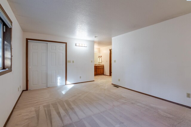 1741 April Loop, Richland, WA 99352 - unfurnished bedroom featuring light colored carpet, a closet, connected bathroom, and a textured ceiling