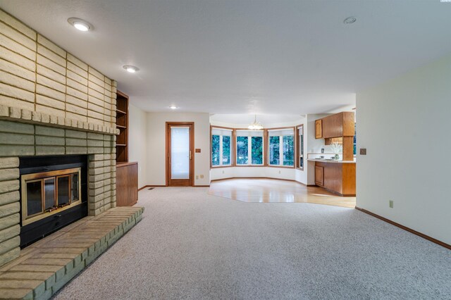 1741 April Loop, Richland, WA 99352 - unfurnished living room featuring light carpet, a brick fireplace, and a chandelier