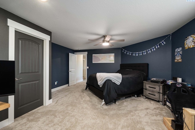 bedroom with ceiling fan, light carpet, and a textured ceiling