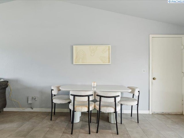 dining room with lofted ceiling, baseboards, and light tile patterned floors