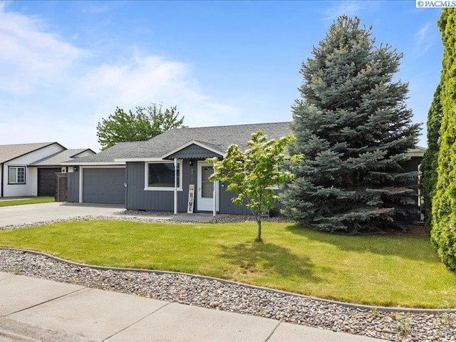 view of front of home with an attached garage, concrete driveway, a front yard, and board and batten siding