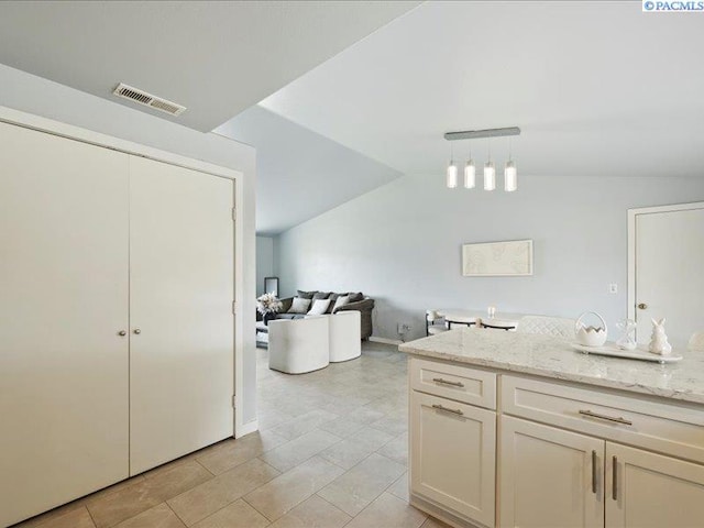 kitchen featuring light stone counters, vaulted ceiling, and pendant lighting