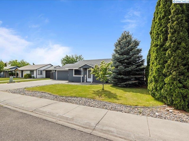 view of front of home featuring concrete driveway, a garage, and a front lawn