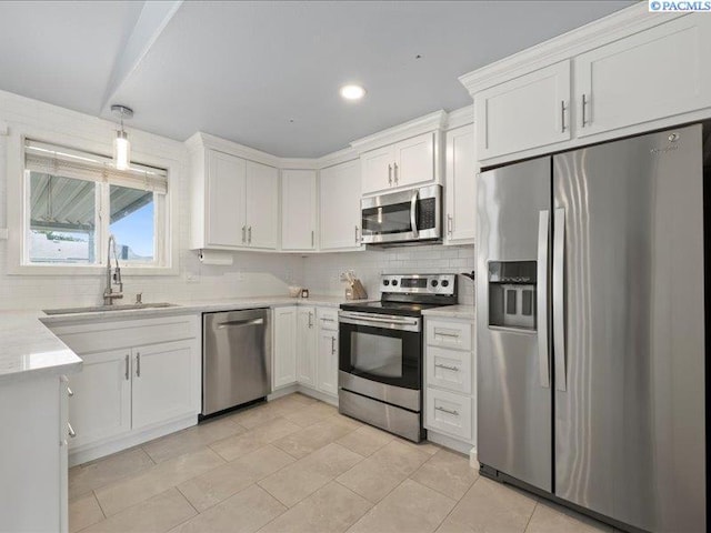 kitchen featuring appliances with stainless steel finishes, a sink, tasteful backsplash, white cabinets, and light tile patterned floors