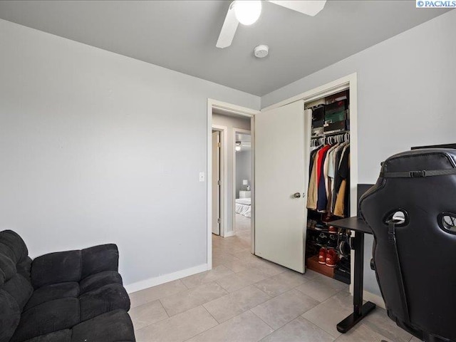 office space featuring a ceiling fan, light tile patterned floors, and baseboards