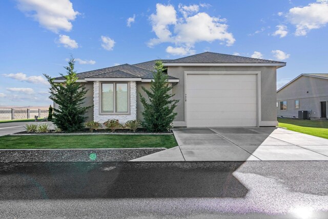 view of front facade with cooling unit, a garage, and a front yard