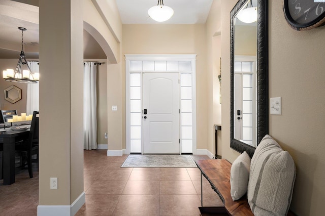 tiled entrance foyer featuring a healthy amount of sunlight and a chandelier