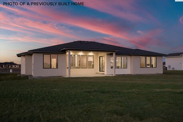 2260 Belfair St Unit 5, Kennewick, WA 99338 - back of house at dusk featuring a lawn, a patio area, and stucco siding