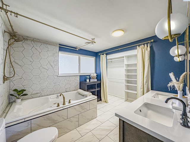 bathroom featuring marble finish floor, double vanity, a spacious closet, a sink, and a bath