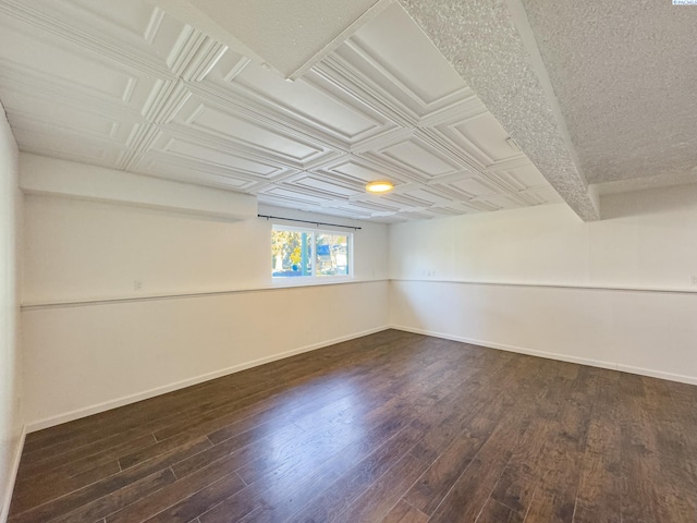 unfurnished room featuring an ornate ceiling, dark wood-style flooring, and baseboards