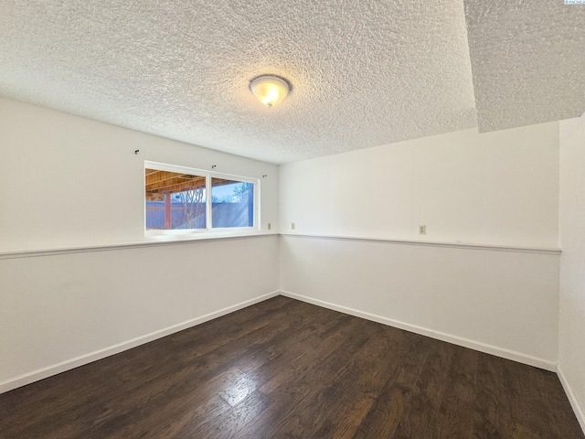 unfurnished room featuring a textured ceiling, dark wood-style flooring, and baseboards