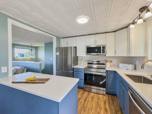 kitchen featuring light countertops, appliances with stainless steel finishes, blue cabinetry, and white cabinetry